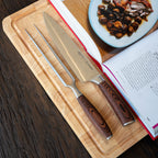 Simplit Set Parrillero Toledo cuchillo 21 cm y tenedor — set sobre la tabla junto a un libro de recetas