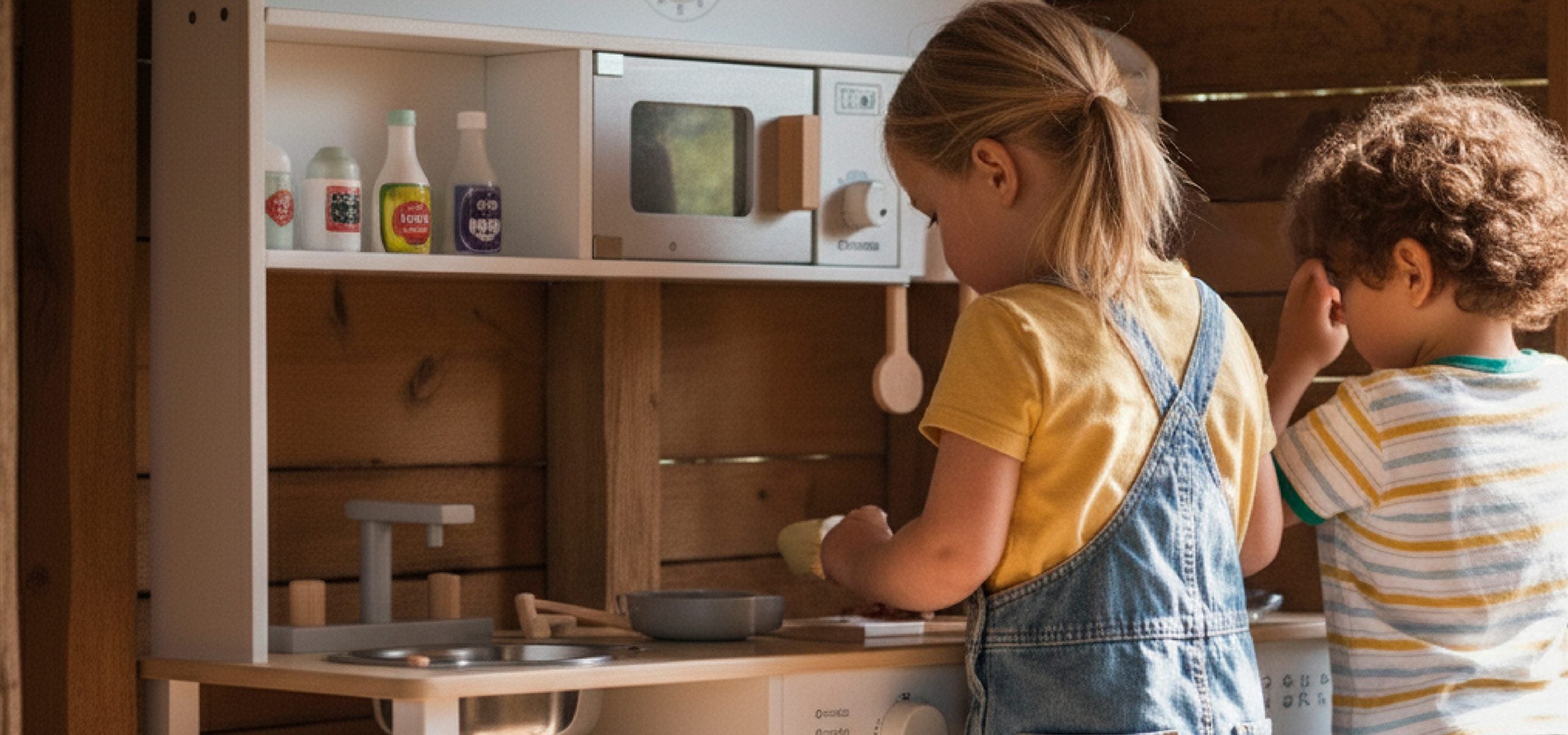Ninos jugando con cocina de madera Bandu en una habitacion calida